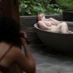 Behind the scenes boudoir photo of nude women in flower bath in Bali